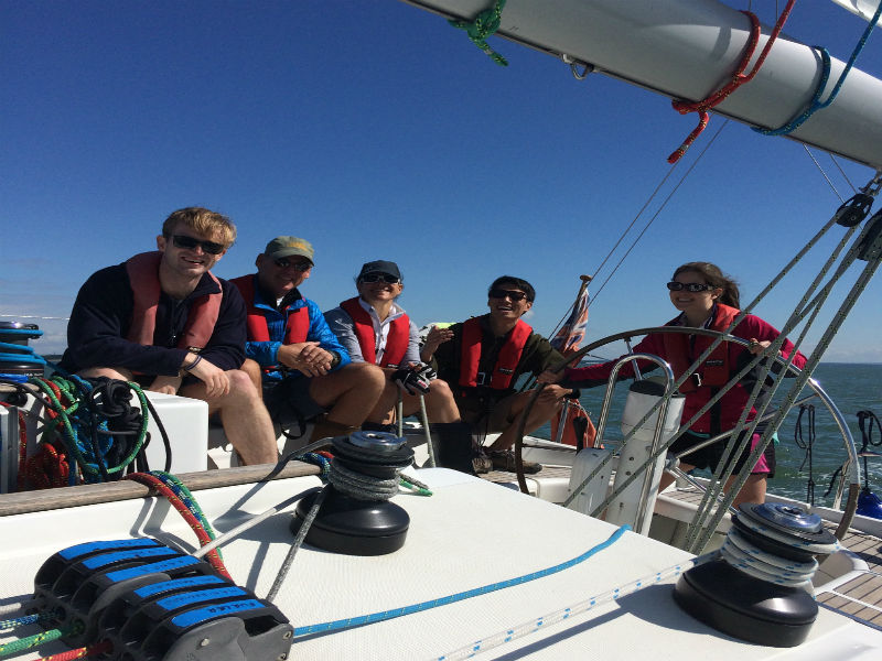 Image of crew sailing a yacht with beautiful blue sky in the background
